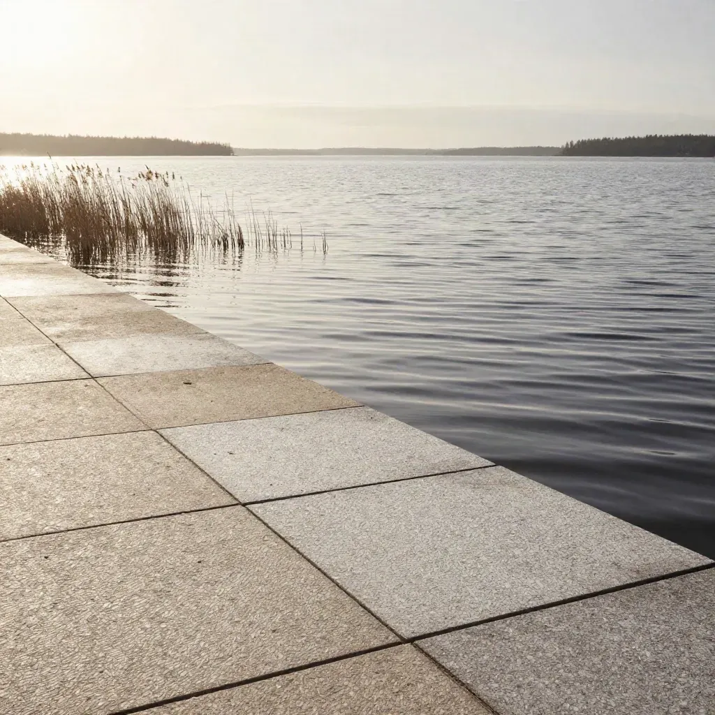 Morgondimmig vy över Mälaren med slottssiluett, vass och ljus stenstrand.